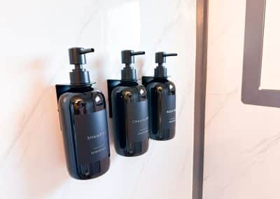 Wall-mounted shampoo, conditioner, and body wash dispensers inside Iron Horse Living bathroom.